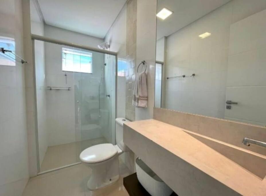 a bathroom with a toilet and a glass shower at AP completo na Praia de Palmas, SC in Governador Celso Ramos