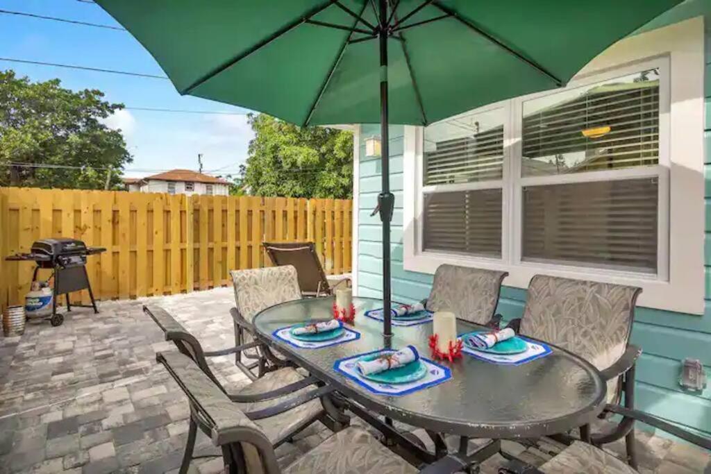 eine Terrasse mit Tisch und Stühlen und einem Sonnenschirm in der Unterkunft Coastal Cottage - Just 7 Minutes to the Beach and Downtown! in Lake Worth