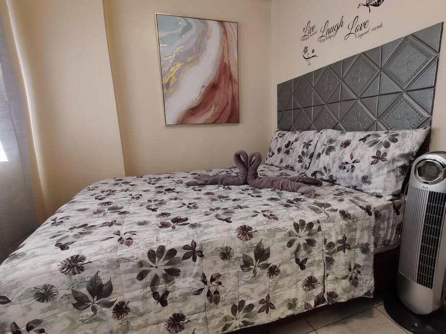 a bedroom with a bed with a floral bedspread at 2BR Charming Condo near Session road and Sm Goshenland Towers in Baguio