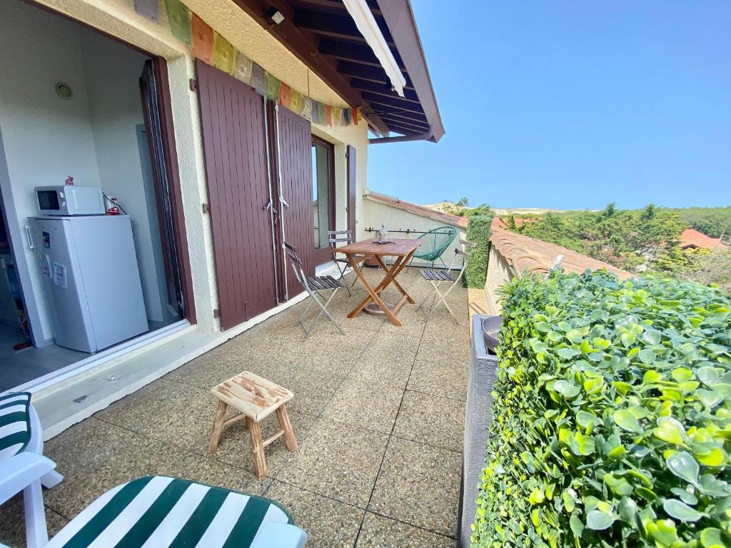 un patio avec une table et des chaises sur un balcon dans l'établissement Appartement lumineux à 4 min de la plage avec terrasse, parking privé et WIFI ! - FR-1-239-999, à Seignosse