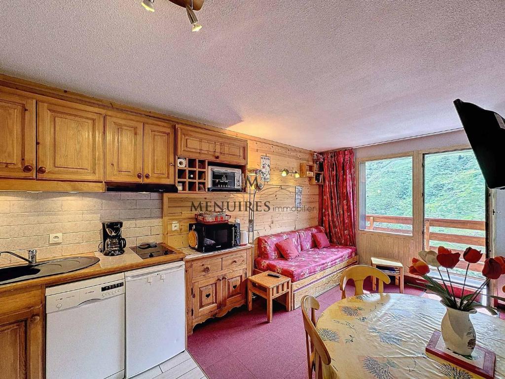 eine Küche mit einem rosa Sofa und einem Tisch in der Unterkunft 2 pièces cabines idéal pour 5 pers, proche pistes, parking, Wi-Fi, animaux admis - FR-1-178-394 in Les Bruyères