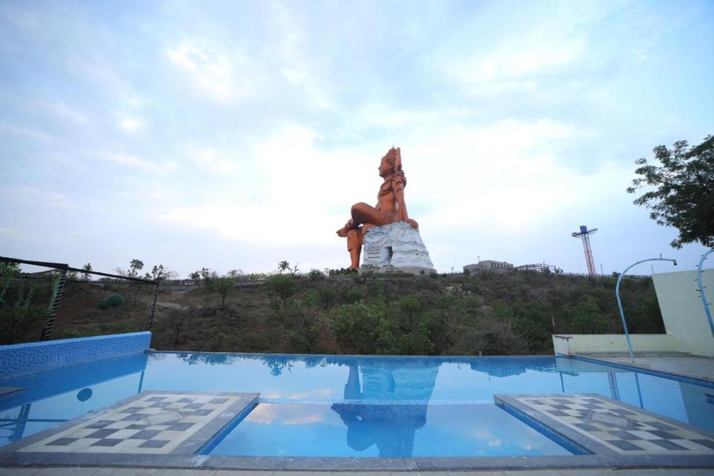 a statue of a woman sitting on a hill next to a pool at Shiv Ashray Resort in Nāthdwāra
