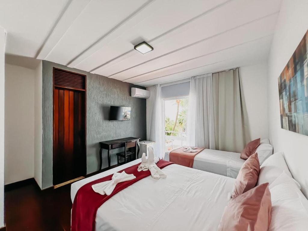 a hotel room with two beds and a couch at Dom Aquino Hotel e Gastronomia in Natal