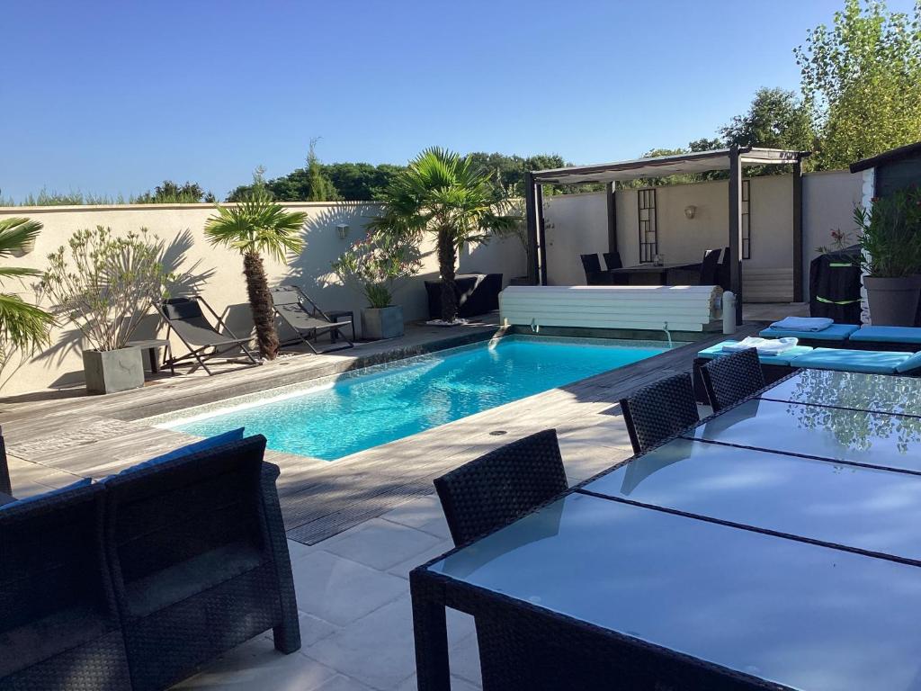 - une piscine avec des tables et des chaises dans l'arrière-cour dans l'établissement Le Passage, à Vineuil