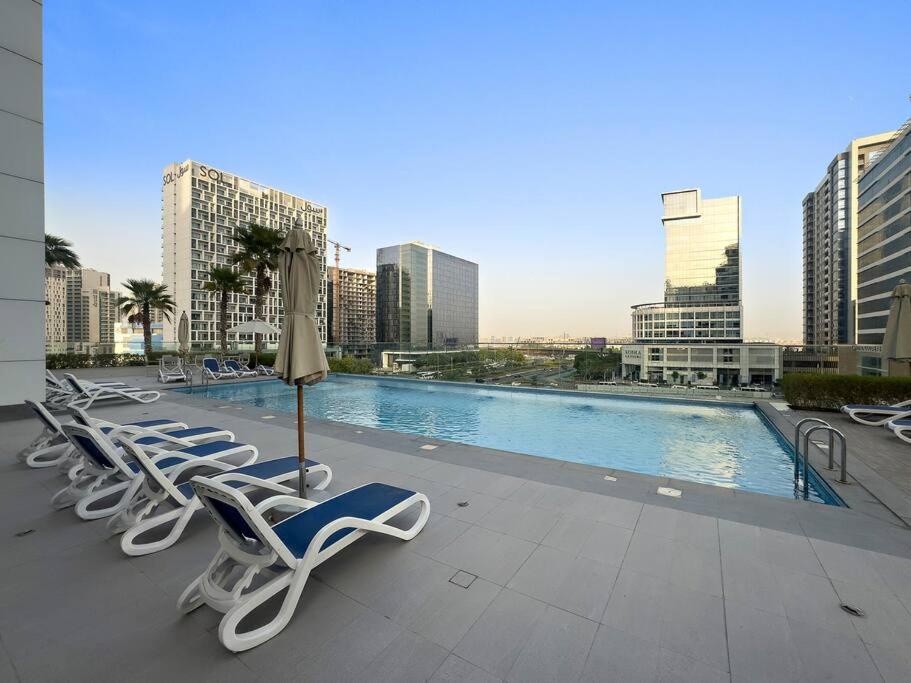una fila di sedie a sdraio e una piscina in città di FIRST CLASS Studio Rustic Charm in SOL BAY a Dubai