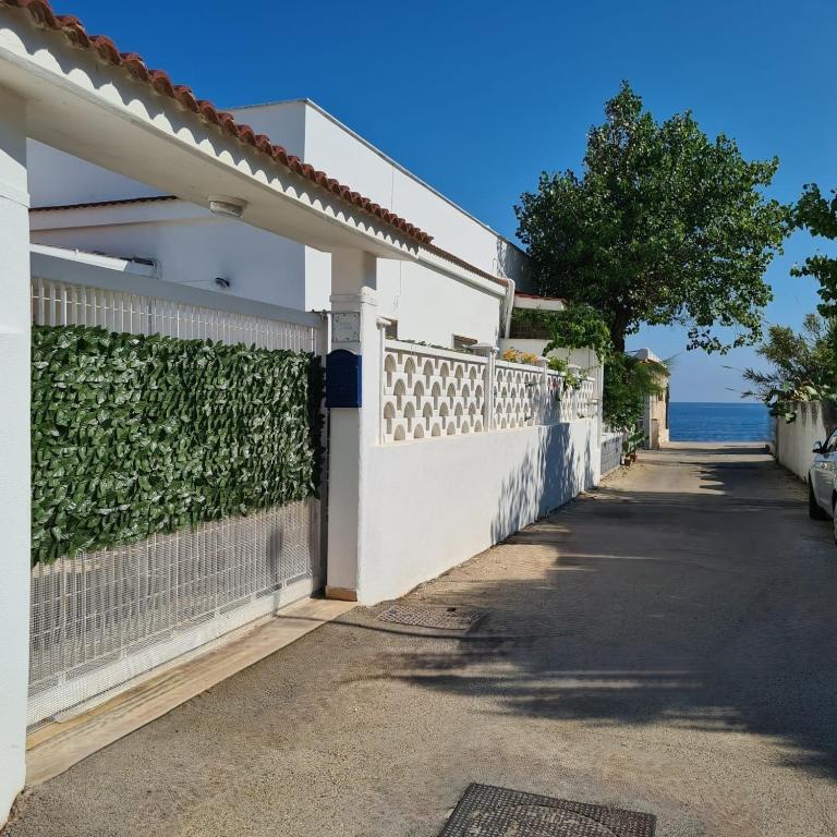 a white house with a green wall and a street at Villa Lilium in Bari