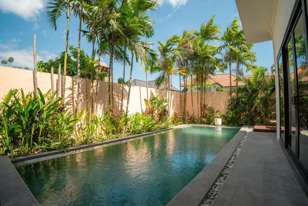 a swimming pool in the backyard of a house with palm trees at Villa GMT Canggu - By Bali Lyfe Venture in Canggu