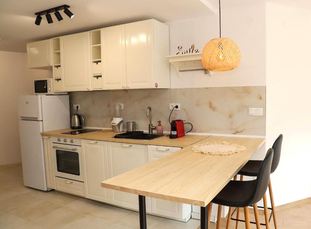 a kitchen with white cabinets and a wooden table at Sophie Studio - Top center, Cozy & Work-Friendly near AUBG, Free streaming platforms in Blagoevgrad