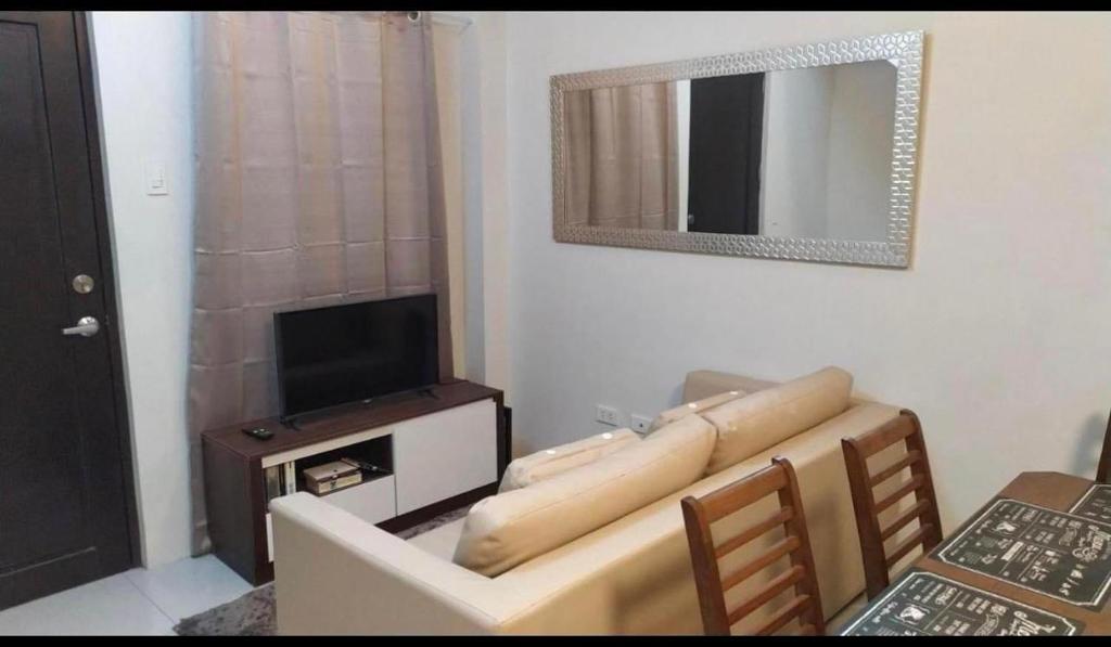 a living room with a couch and a television at Mactan Guesthouse in Cogon