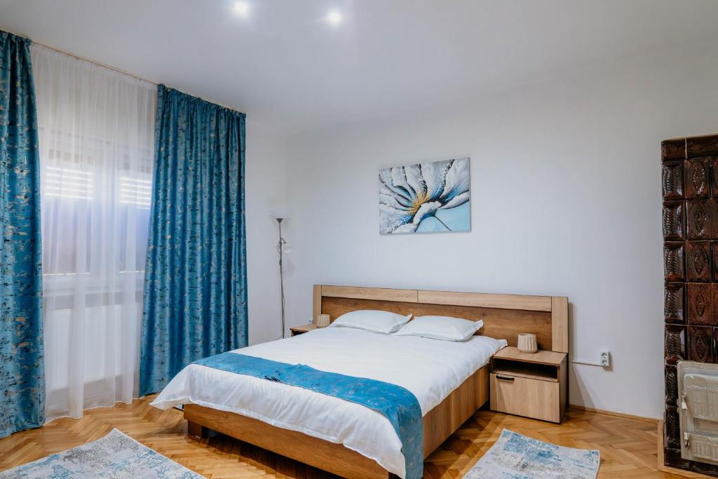 Un dormitorio con una cama grande con cortinas azules. en Vi La June, en Chimindia