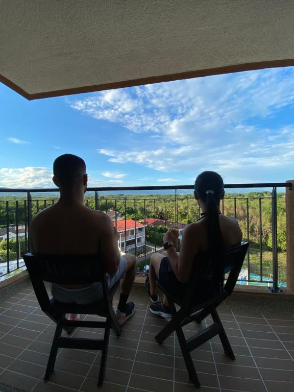 deux personnes assises sur des chaises sur un balcon regardant la vue dans l'établissement Apartamento de verano, à San Rafael