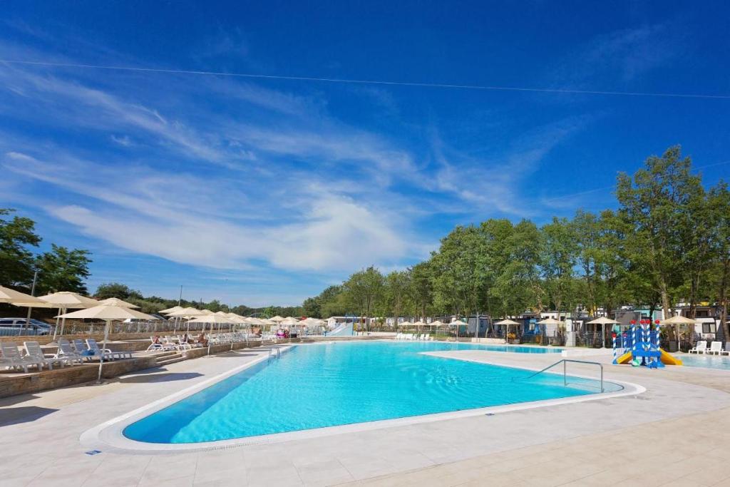a large swimming pool with chairs and umbrellas at Residence SCOPA 2 in Poreč