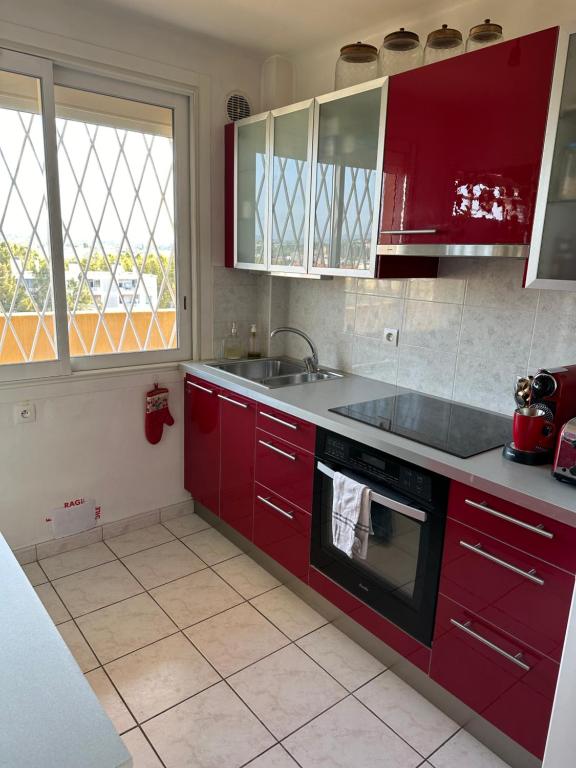 une cuisine avec des armoires rouges et un évier dans l'établissement Charmant Appartement de 42 m à 200 m de la Plage, à Fréjus