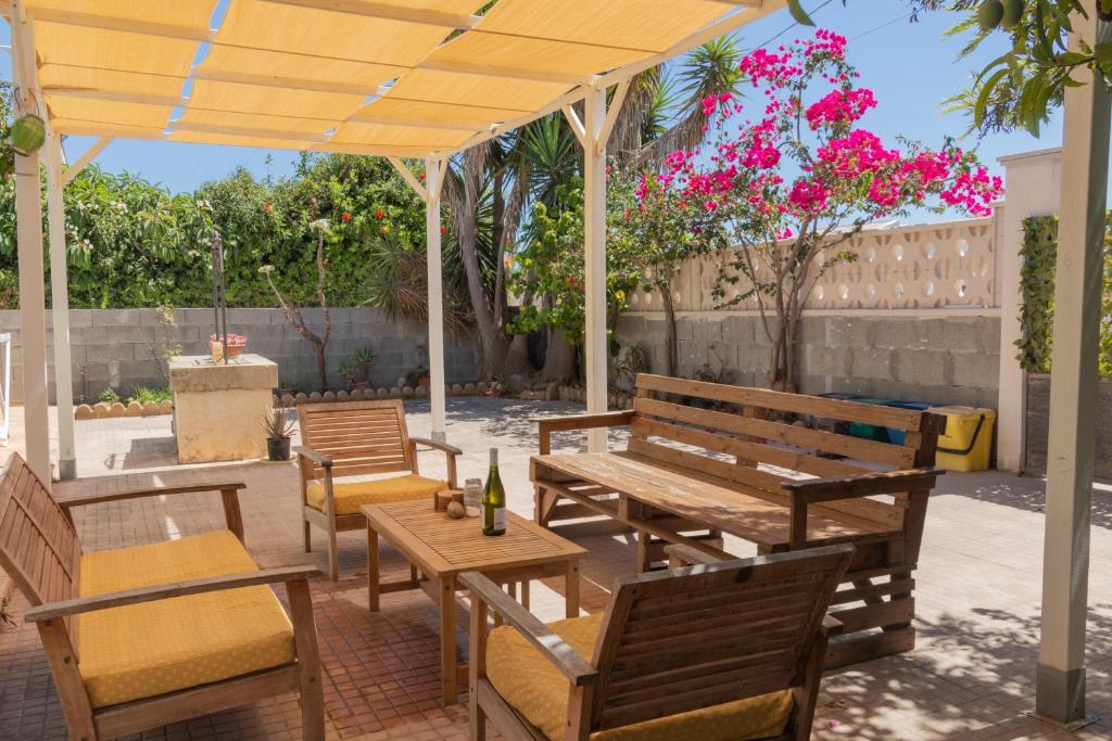 a patio with wooden benches and tables and flowers at Amaris Mango Seafront Villa in Granelli