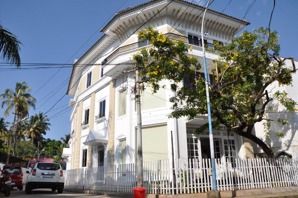 a white house with a white fence in front of it at Daffodils Spice Court in Cochin