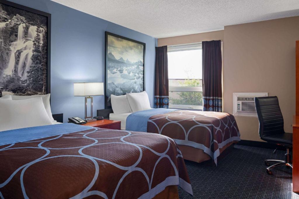 a hotel room with two beds and a window at Super 8 by Wyndham Sherwood Park/Edmonton Area in Sherwood Park