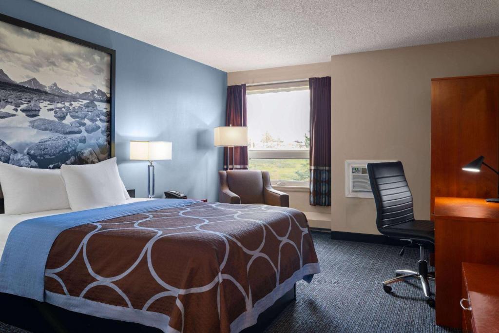 a hotel room with a bed and a desk and a chair at Super 8 by Wyndham Sherwood Park/Edmonton Area in Sherwood Park