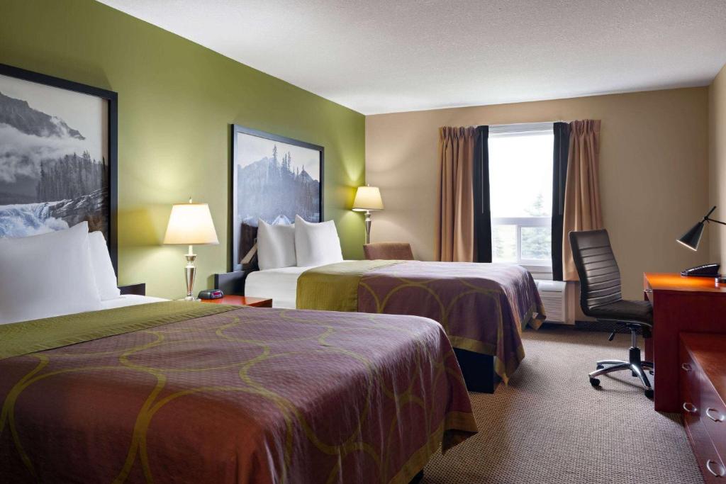 a hotel room with two beds and a desk at Super 8 by Wyndham Sherwood Park/Edmonton Area in Sherwood Park