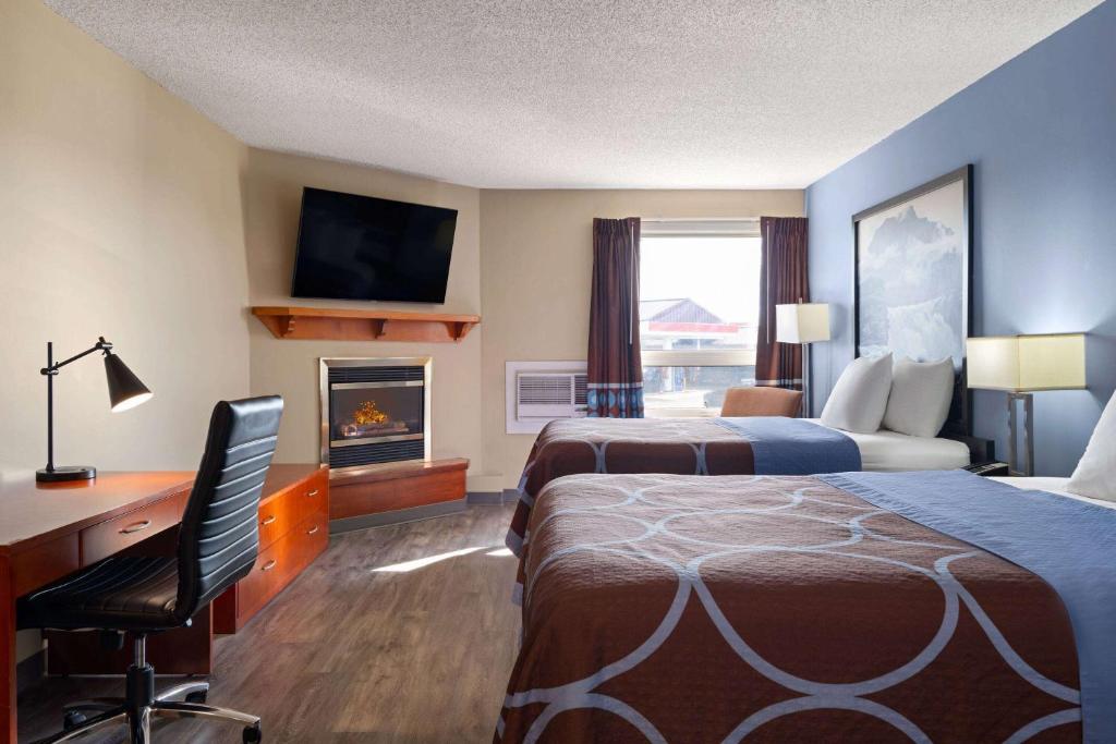 a hotel room with two beds and a desk and a fireplace at Super 8 by Wyndham Sherwood Park/Edmonton Area in Sherwood Park