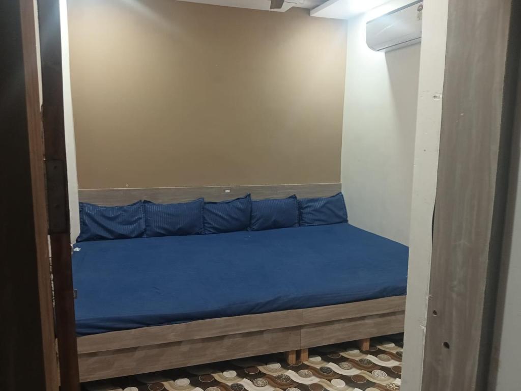 a small bed in a room with blue sheets at Atharva home stay in Ujjain