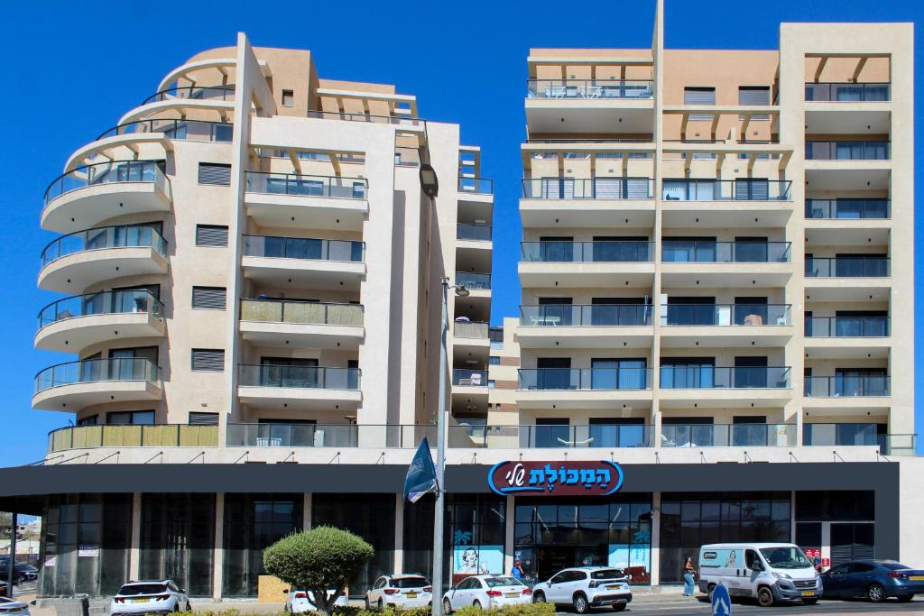 a large building with cars parked in front of it at Luxury Family Apartment #30 By Hashdera Eilat in Eilat