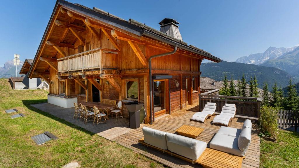 Cette grande maison en bois dispose d'une terrasse avec des chaises. dans l'établissement Chalet Vallée de Chamonix Randonnées, Rafting et Spa, à Saint-Gervais-les-Bains