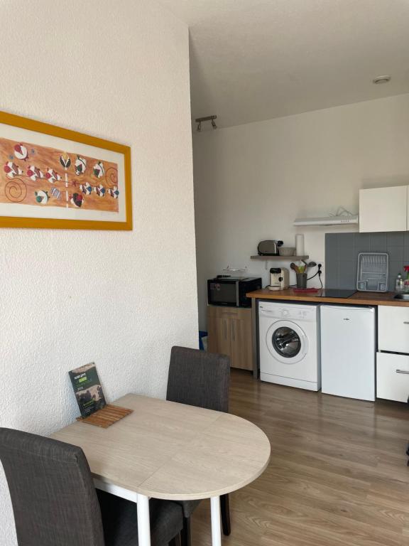 a table and chairs in a kitchen with a table and a dining room at Studio lumineux au calme en centre ville, face aux thermes in Salies-de-Béarn
