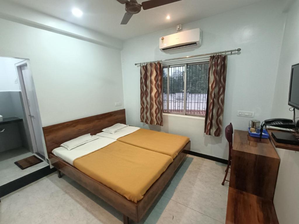 a bedroom with a bed and a desk and a window at Hotel Parth Residency in Kolhapur