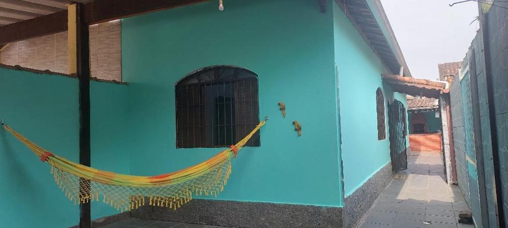 a blue building with a hammock on the side of it at Sua casa longe de casa in Mongaguá