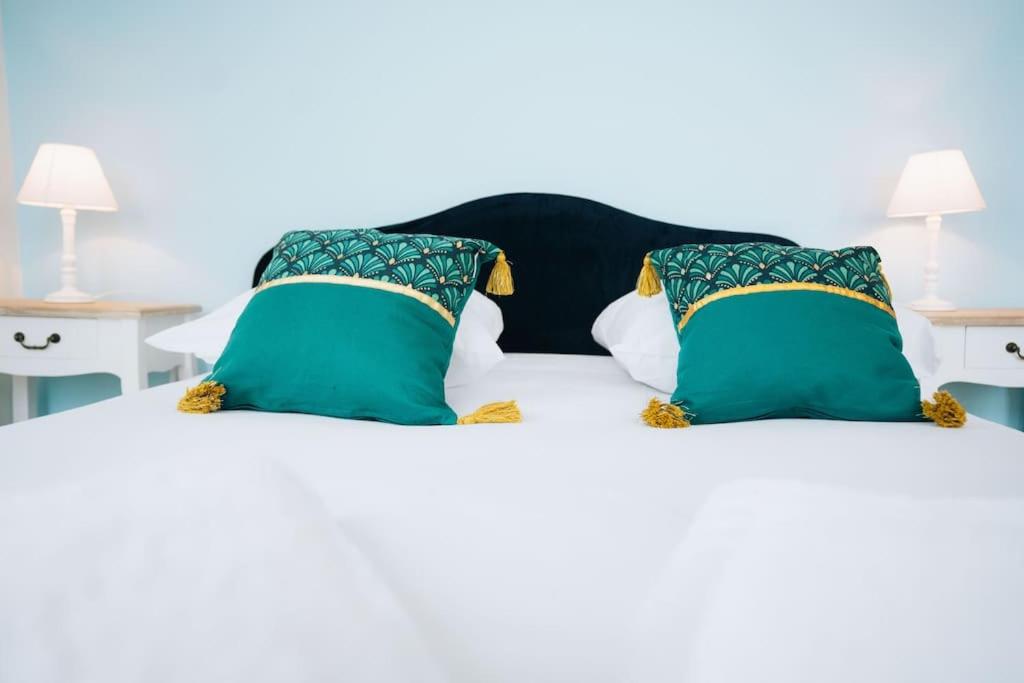 ein Bett mit zwei grünen Kissen darüber in der Unterkunft L'Écrin - Stationnement Privatif - Coeur de ville in Châteauroux