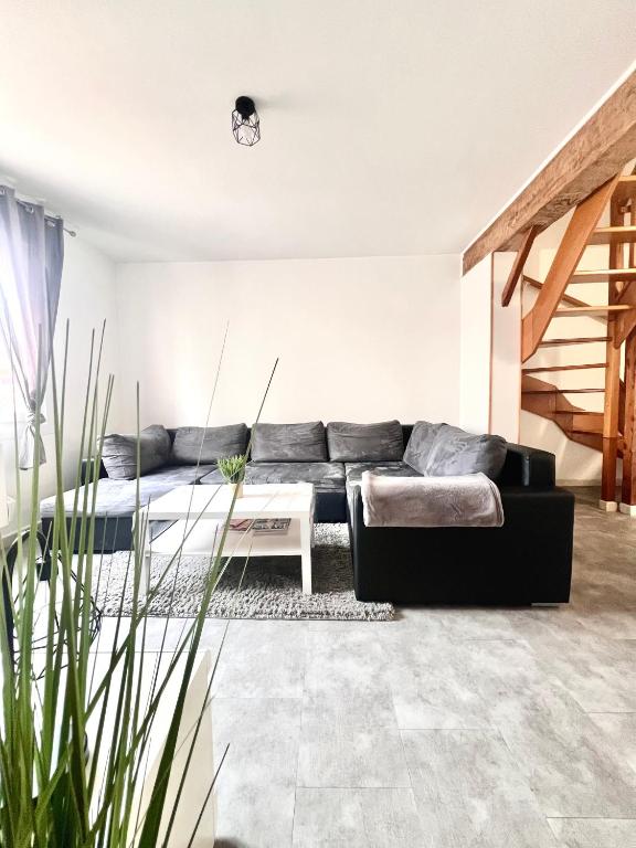 a living room with a black couch and a table at La Verrière d'Opale - Maison proche plage et CNPE EDF in Grand-Fort-Philippe