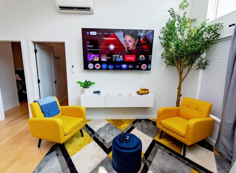 a living room with two yellow chairs and a tv at LuxQuarters Huckleberry Suite in Kitimat