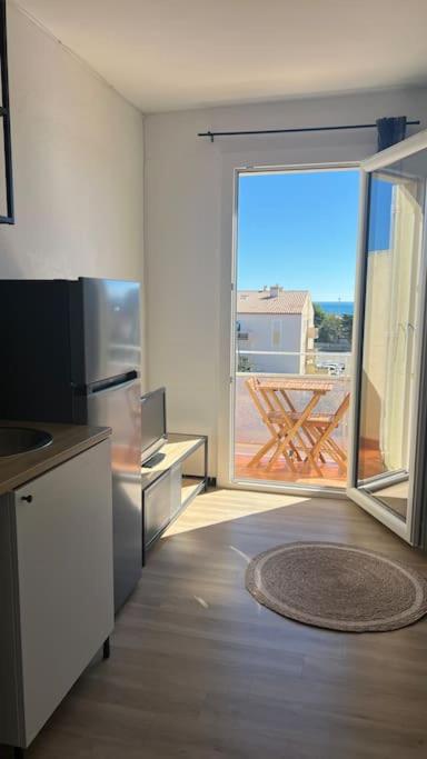 une cuisine avec une porte ouverte sur un balcon dans l'établissement Soraya 16, à Port-la-Nouvelle