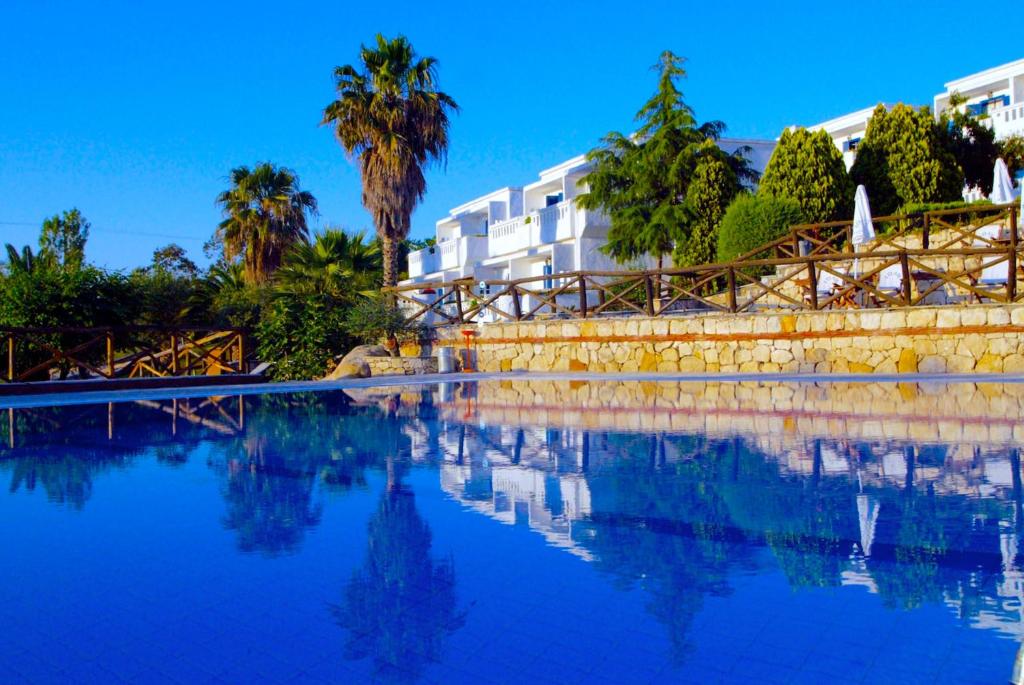 a pool of water with palm trees and a building at Agionissi Resort in Ammouliani