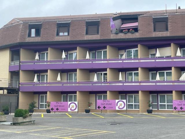 a large building with signs in a parking lot at Eh!Toi Self Motel in Etoy
