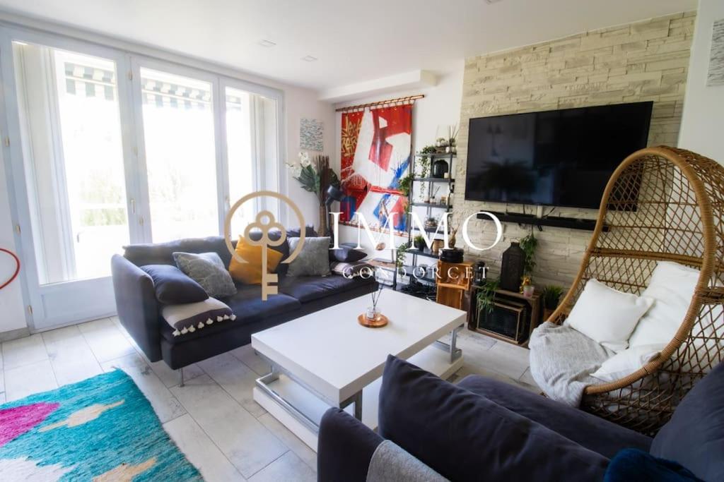 un salon avec un canapé, des chaises et une télévision dans l'établissement Aux portes de Paris, à LʼHay-les-Roses