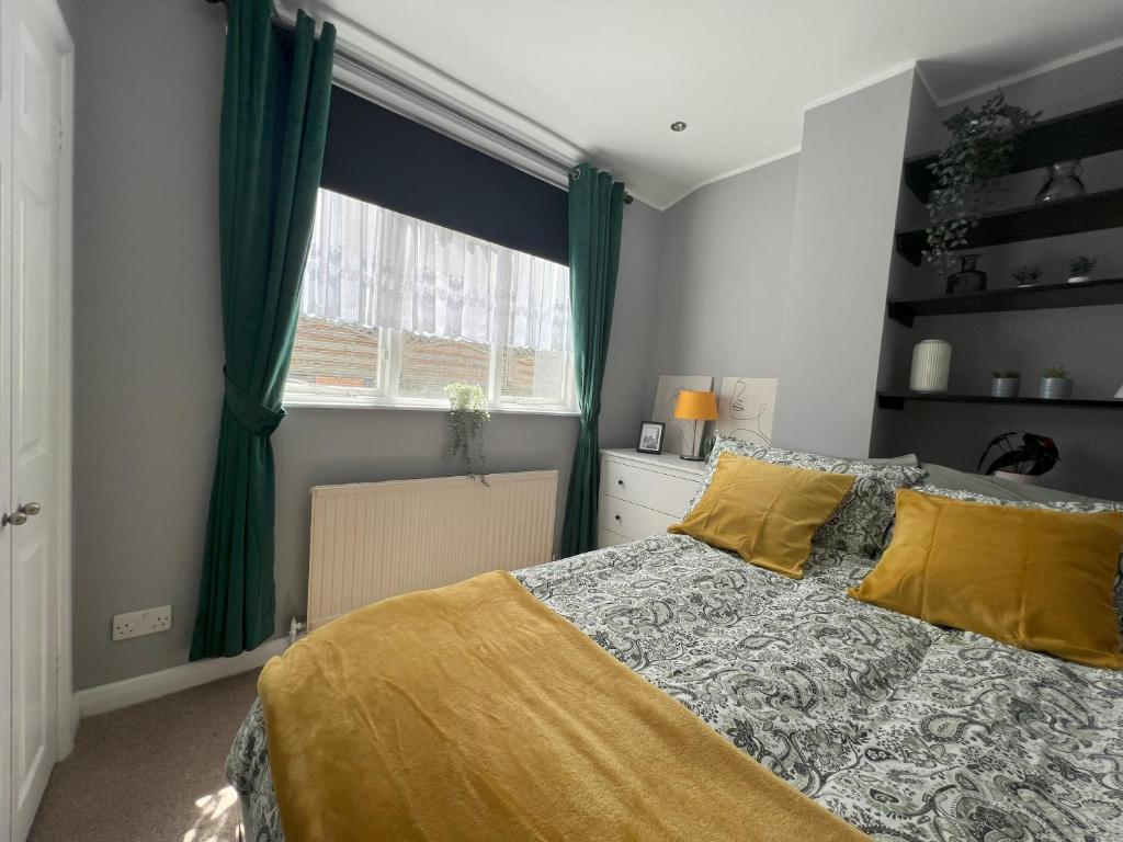 a bedroom with a bed with yellow pillows and a window at Two Bedroom Flat in London in London