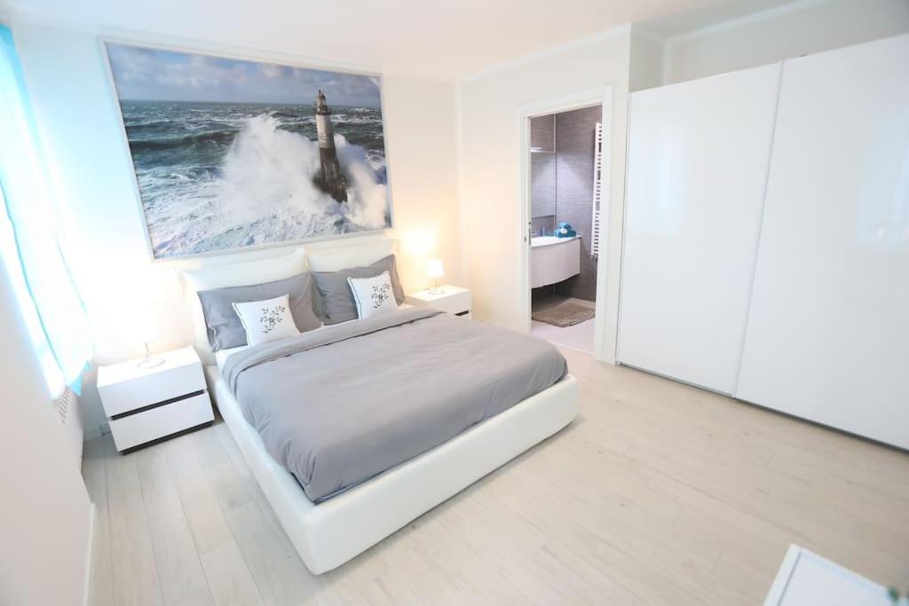 a white bedroom with a bed and a large painting at Casa Magenta Apartment 2 in Valeggio sul Mincio