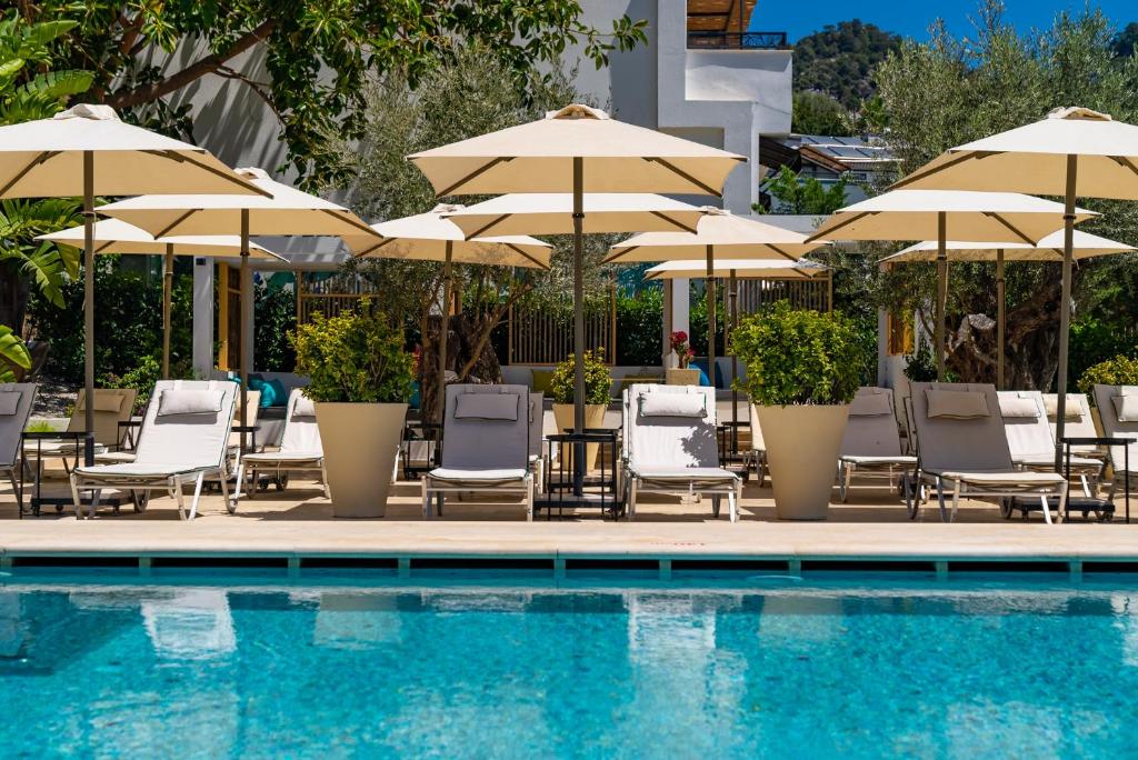 a swimming pool with chairs and umbrellas next to a swimming pool at Ölüdeniz Blu Luxury Unique Hotel - Adults-Only in Oludeniz