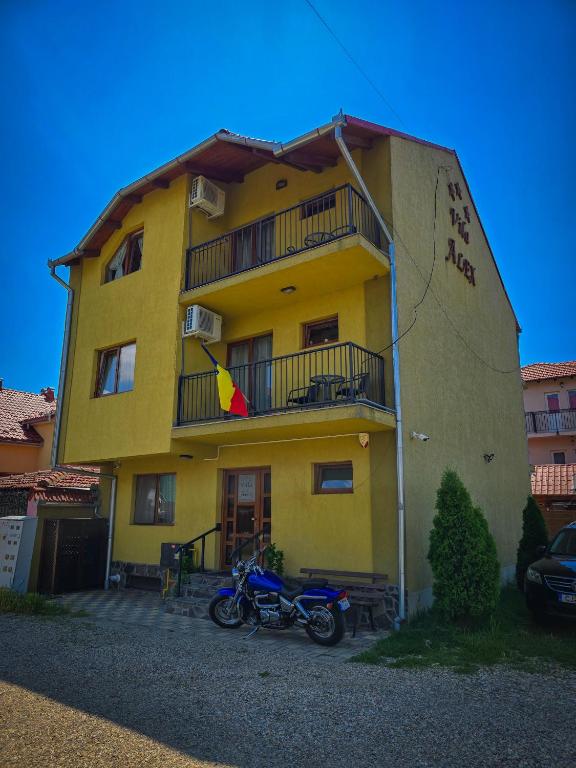 a motorcycle parked in front of a yellow building at Vila Alex in Tăşnad