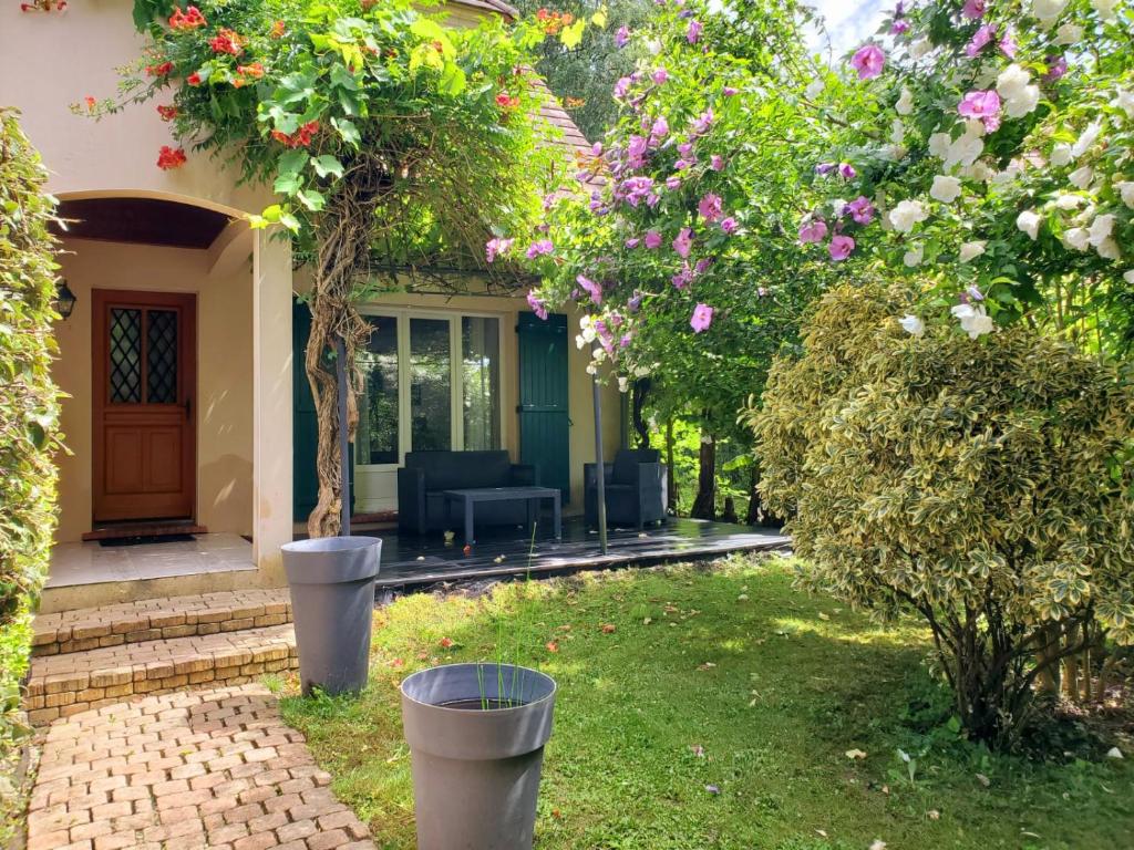 une maison avec un jardin agrémenté d'une terrasse et de fleurs dans l'établissement Belle Maison Sud Seine-et-Marne, à Rubelles