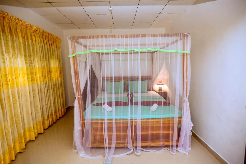 een slaapkamer met een hemelbed in een kamer bij Sinharaja Hostel 114 in Deniyaya