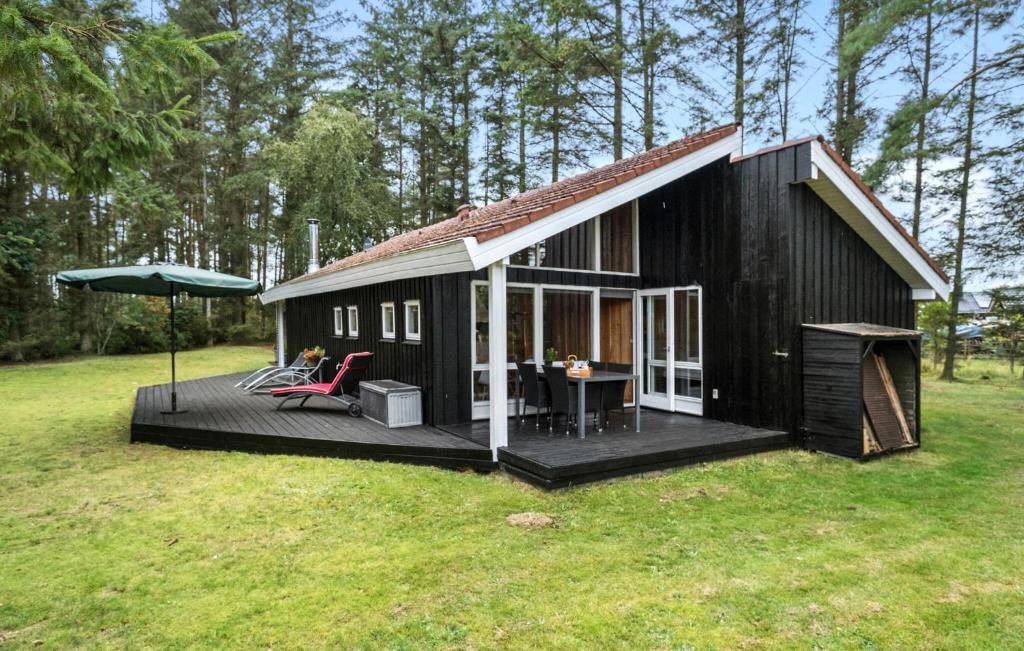 a black house with a deck and an umbrella at Holiday Home Thomas Winthersvej in Hals