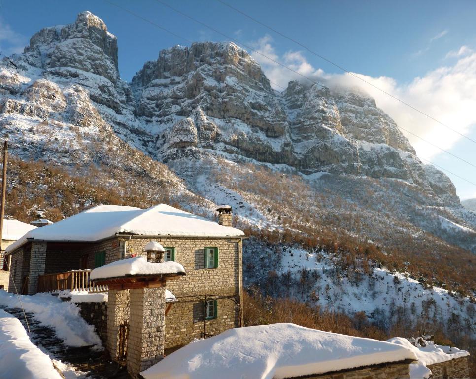 a house in front of a mountain in the snow at Guesthouse Iro in Papingo