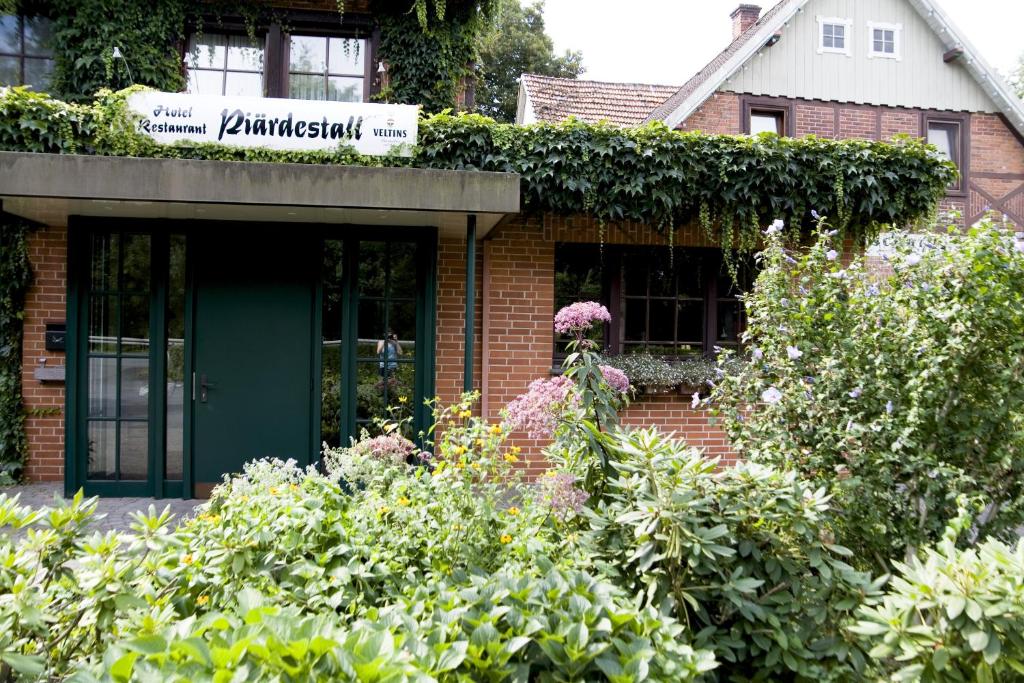ヘーフェルホーフにあるHotel Restaurant Piärdestall Hövelhofの緑の扉と植物のあるレンガ造りの建物