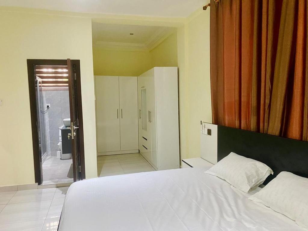 a bedroom with a white bed and a bathroom at SMK Luxury Apartments Ho in Kodjobi