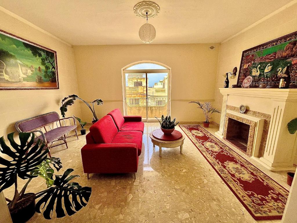 a living room with a red couch and a fireplace at Room in Typical Maltese Maisonette 2 in Taʼ Ċikkun