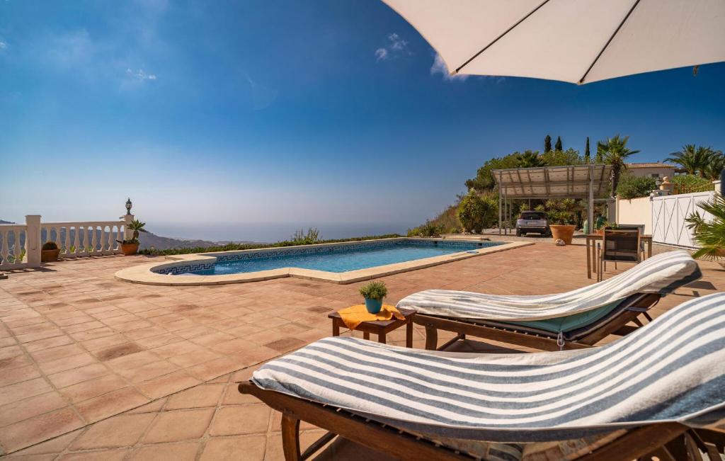 een zwembad met 2 ligstoelen en een parasol bij 1 Bedroom Gorgeous Home In Arenas in Arenas