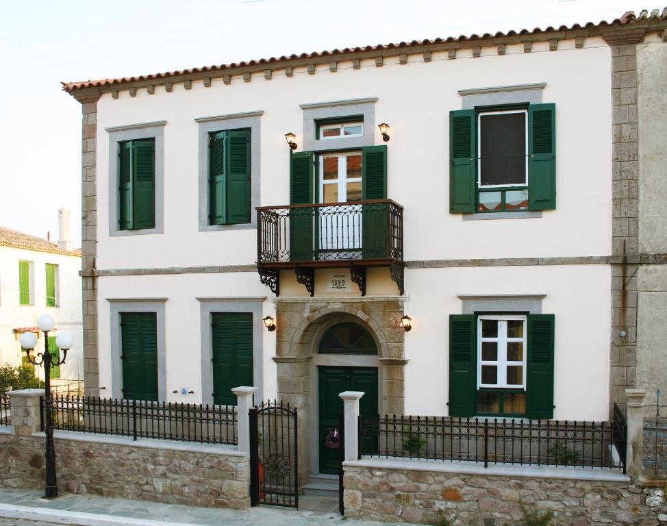 a white house with green shutters and a balcony at Artemis Traditional Hotel in Myrina