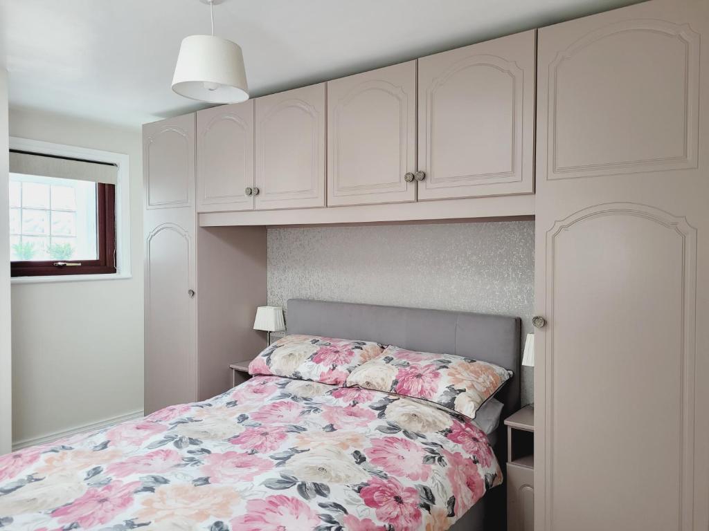 a bedroom with a bed with a floral bedspread at Modern town centre apartment in Tobercurry